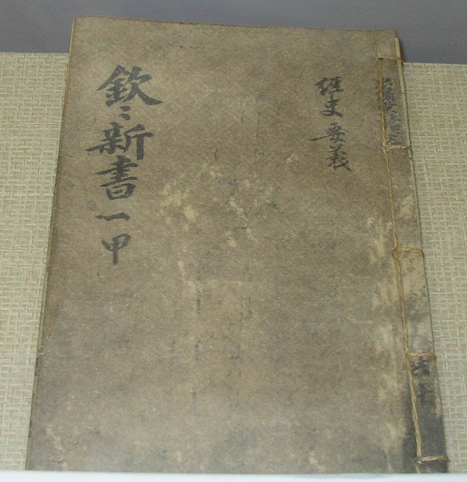 A thread-bound copy of Hŭmhŭm sinsŏ with its title written vertically on the worn paper cover.
